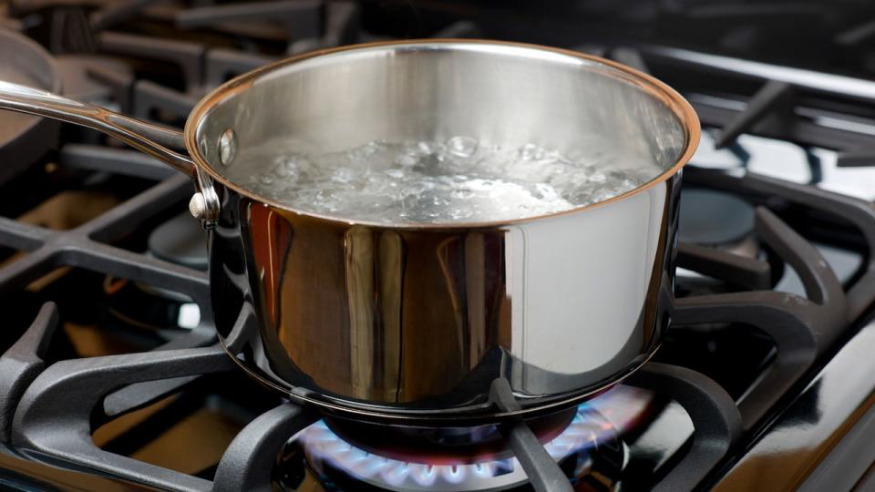 Water bubbles and boils on a gas stove or range in a home kitchen.