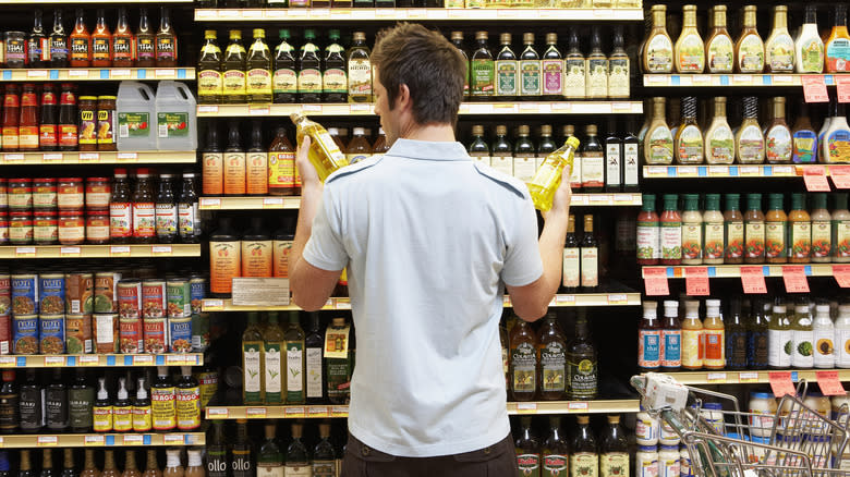 person comparing oils in grocery store