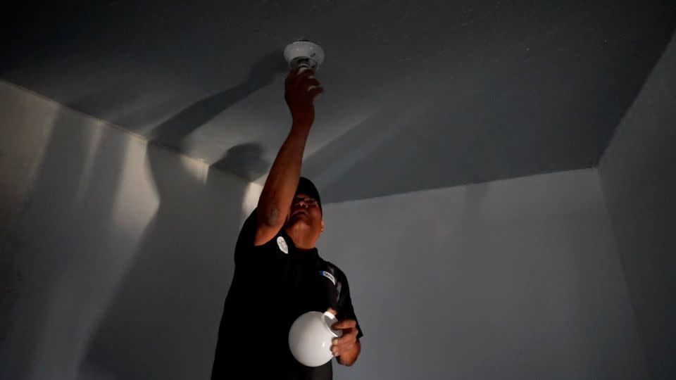 William Lee Tom Jr. screws in a lightbulb at his Navajo Nation home. - Joel De La Rosa/CNN