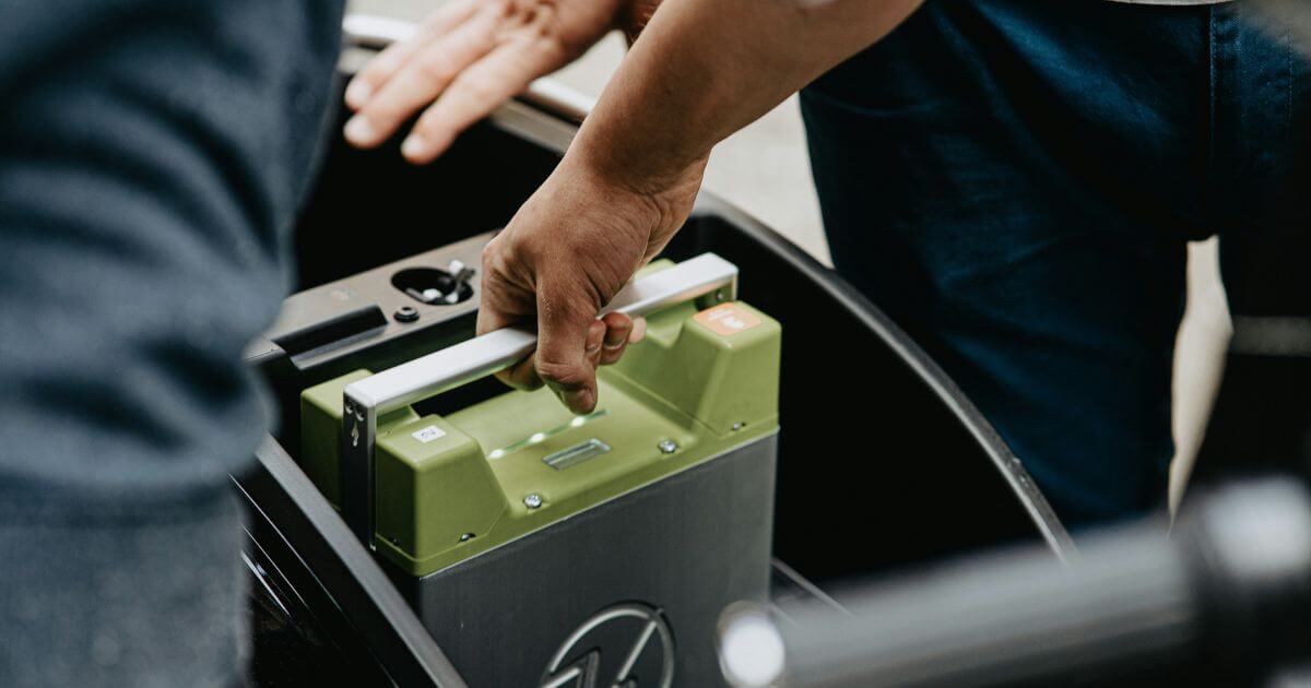 Worker holding a black and green electronic battery and device