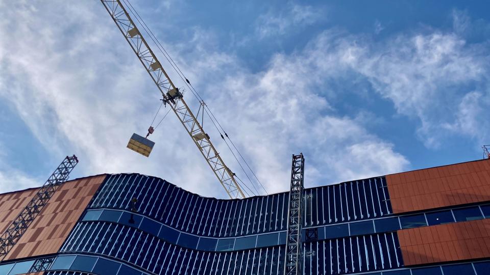 A crane carries a crate of solar panels to the roof of the Bob Crane Community Center under construction Wednesday in Upper Arlington.