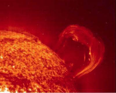 A loop of red plasma extends out from the surface of the Sun.