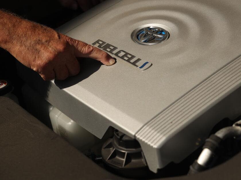 A main points at the Toyota fuel cell badging on his car. 