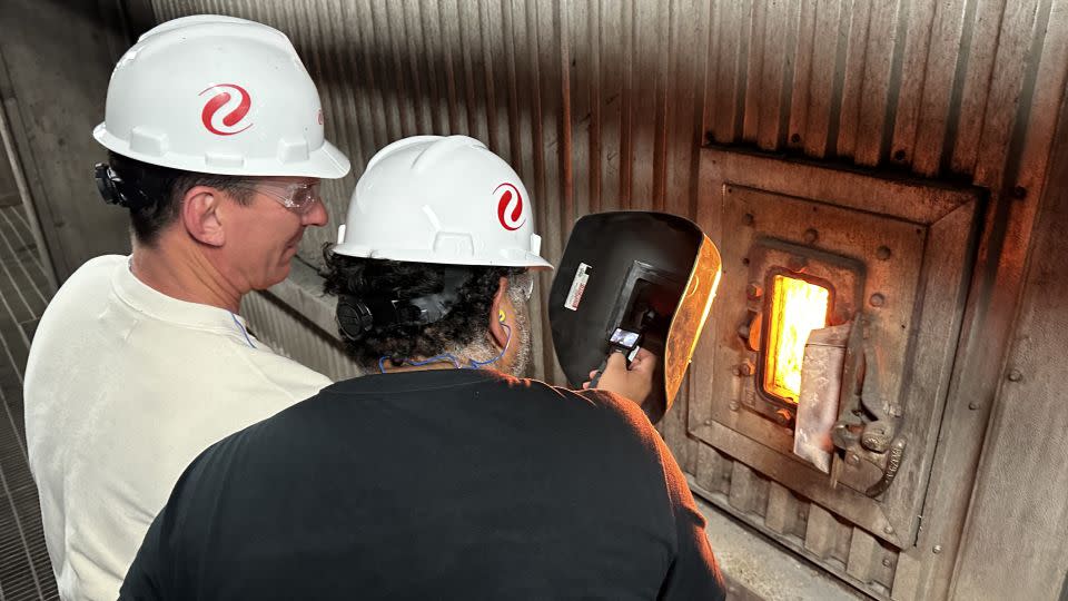 CNN's Bill Weir looks at the coal fire that generates energy for thousands of customers through a protective welder's mask. - Julian Quinones, CNN