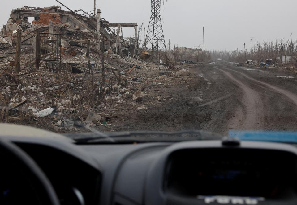 A view from a car shows the rubble of destroyed buildings.