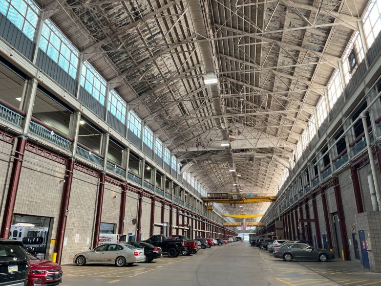 An indoor shot of a tall, wide factory with parked cars.