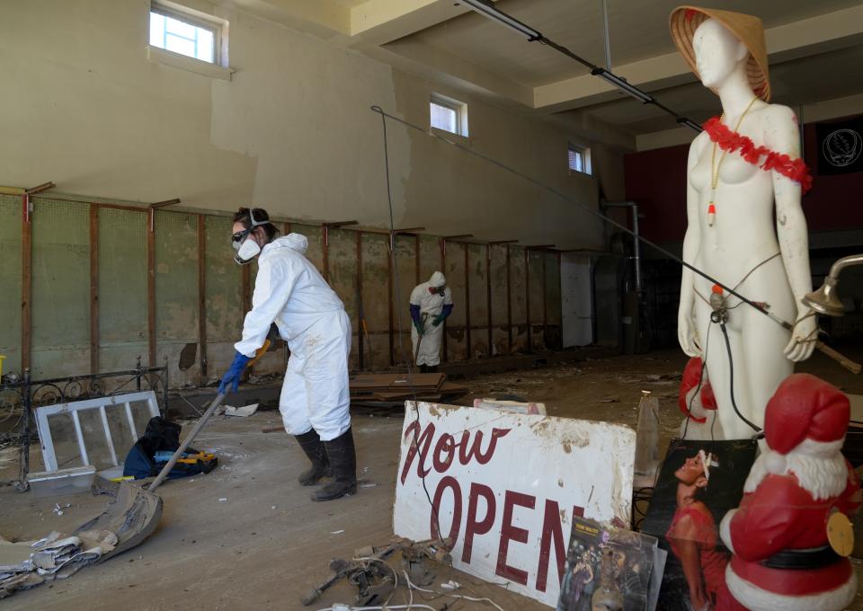 Caroline Keys, 31, from Asheville, N.C., shovels debris out the door of a flooded building in Marshall, N.C., on Oct. 10, 2024. The city of Marshall experienced flooding caused by the tropical storm winds and rain brought by the remnants of Tropical Storm Helene.