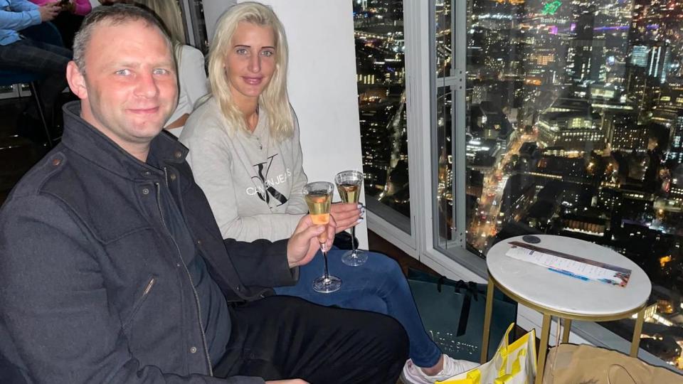 Couple sit in a bar with a view across London at night 