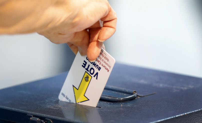 A voter deposits a voting card into a ballot box during the first day of early voting in Nevada. 