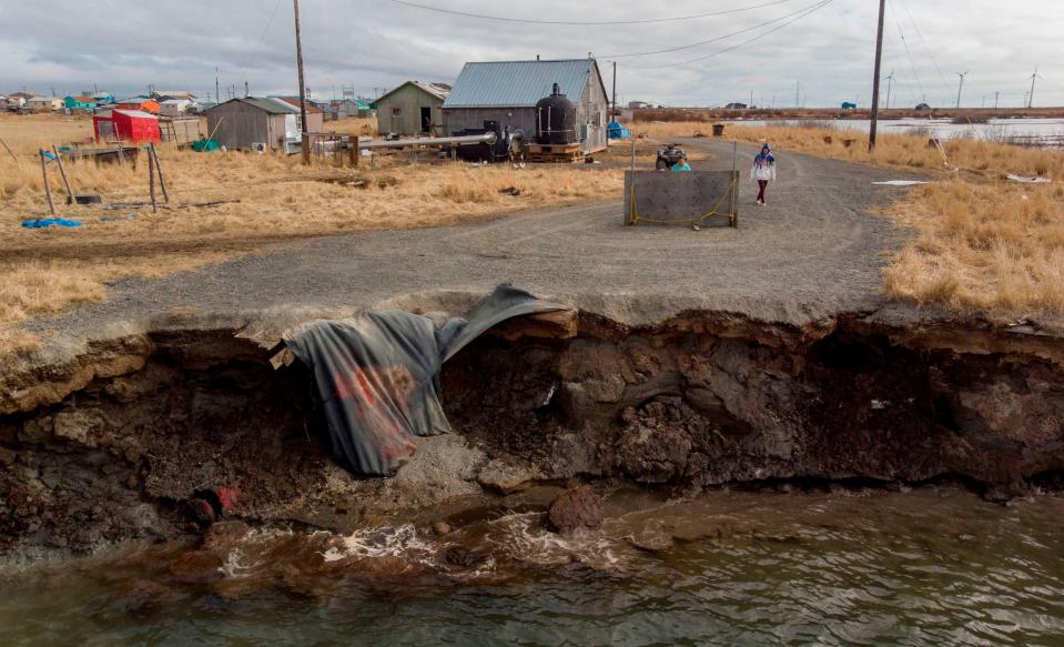 gravel road abruptly ends crumbling into running water two feet below in rural setting with a few homes