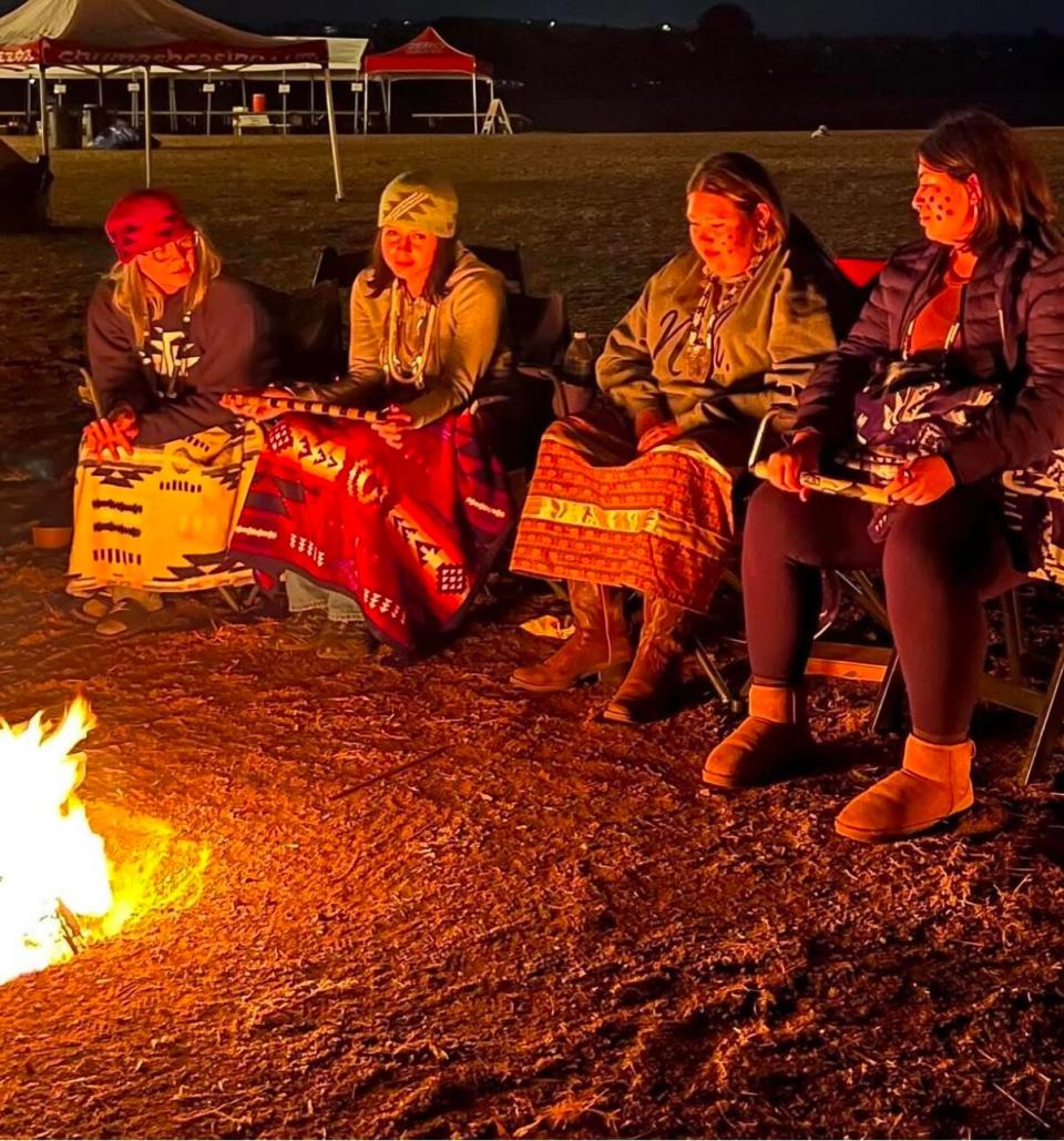 Four Indigenous women gather around a fire  in California.