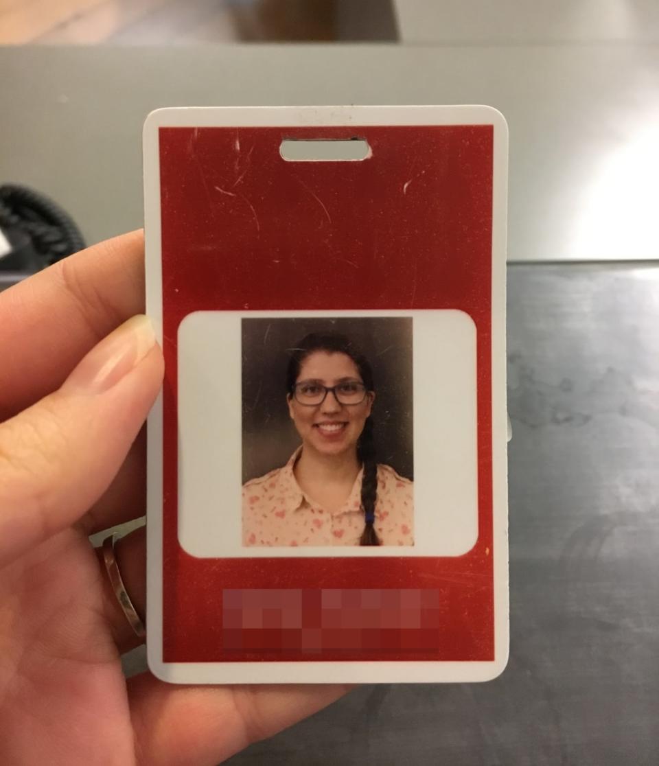 A hand holds an ID badge showing a portrait photo