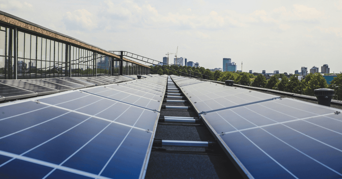 Black and white solar panels on a building with the city skyline in the background.