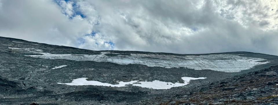 dirty grey long patch of ice on a mountainside with a whiter strip of snowy ice below