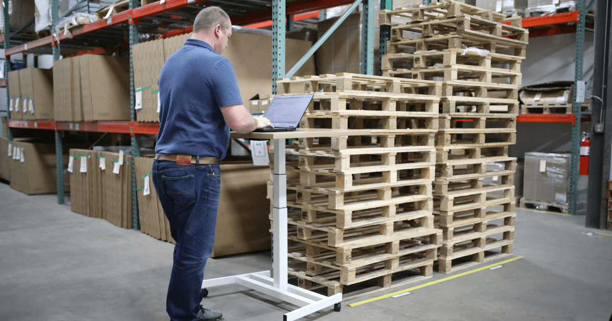 Worker standing in pallets in a warehouse using warehouse management software to make use of intelligent technology