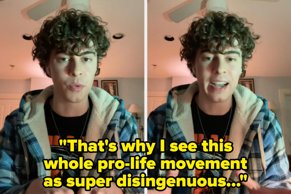 Person with curly hair wearing a plaid jacket over a graphic t-shirt, speaking expressively indoors