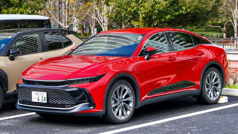A red Toyota Crown Crossover parked on a the city street.