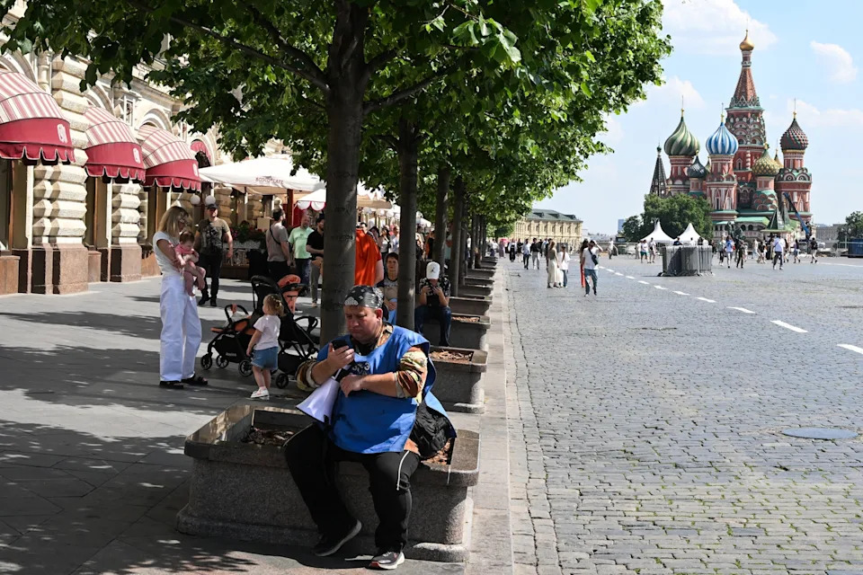 Igor Ivanko/AFP via Getty Images - PHOTO: People sit in shade with St Basil's Cathedral in the background during a hot day in central Moscow on June 10, 2026.