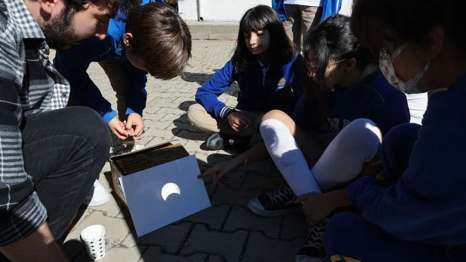 People observe a partial solar eclipse on a paper through a telescope in Ankara, Turkey, on October 25, 2022. - Adem Altan/AFP/Getty Images