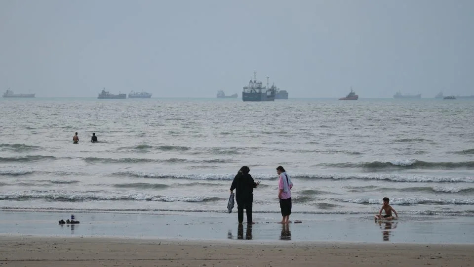 People spend time at a beach as commercial vessels are anchored in the Strait of Hormuz off Bandar Abbas, Iran, on Wednesday, Sept. 2. - Razieh Poudat/ISNA/AP